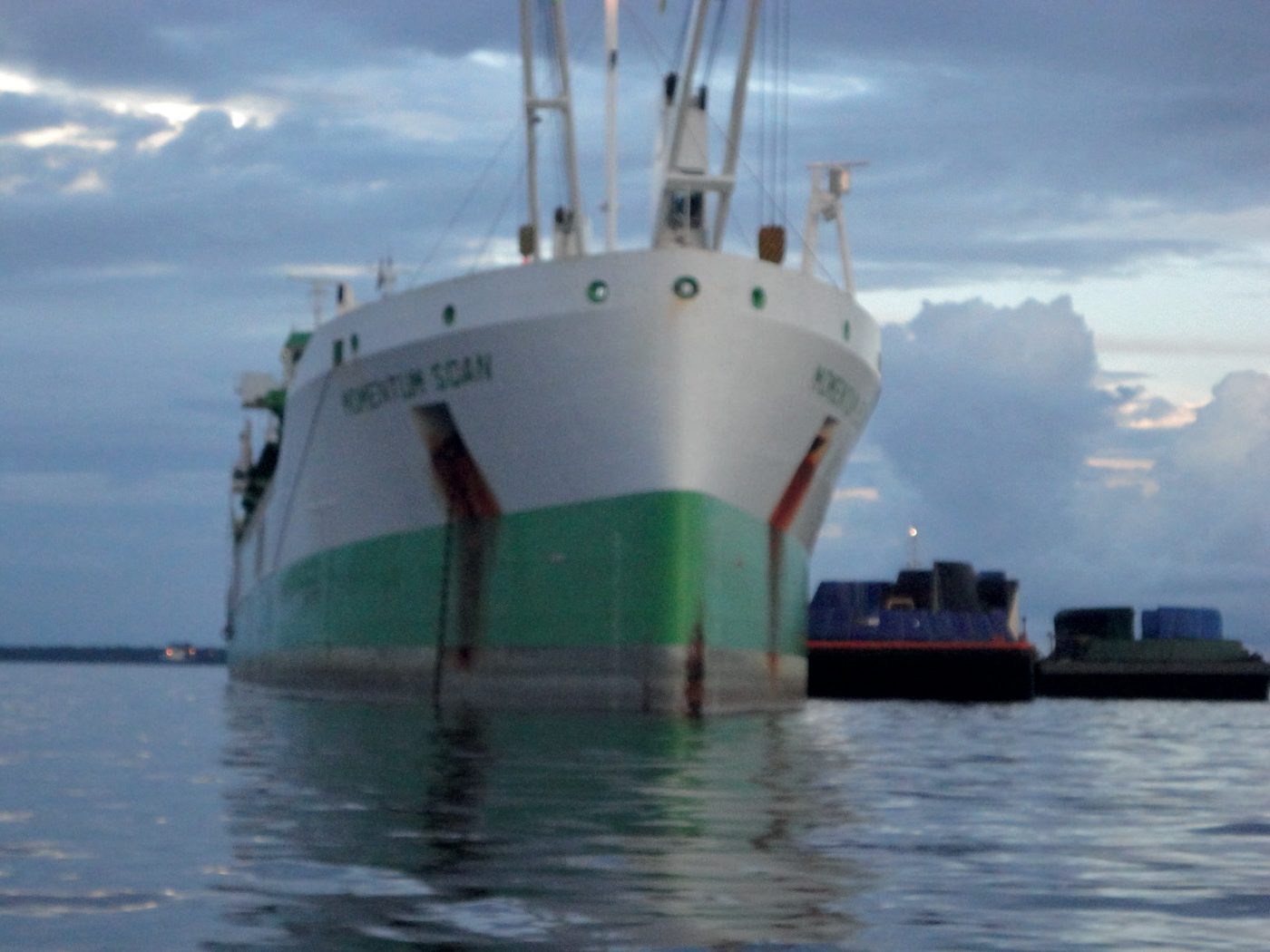 Navio de carga ancorado ao lado de balsas em rio da Amazônia