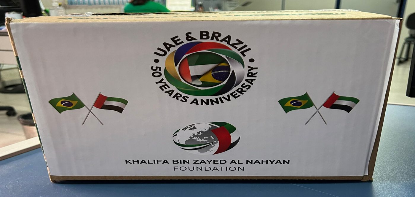 Caixa do projeto humanitário entre Emirados Árabes Unidos e Brasil, com as bandeiras dos dois países